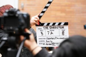Home Close-up of film clapperboard in action with camera filming a take on set.